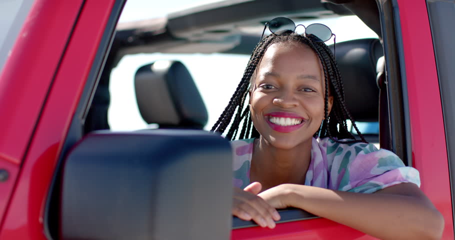 African American woman smiles from a car window on a road trip with copy space. Her joyful expression suggests a sense of freedom and adventure on the road, slow motion. Royalty-Free Stock Footage #3447629439