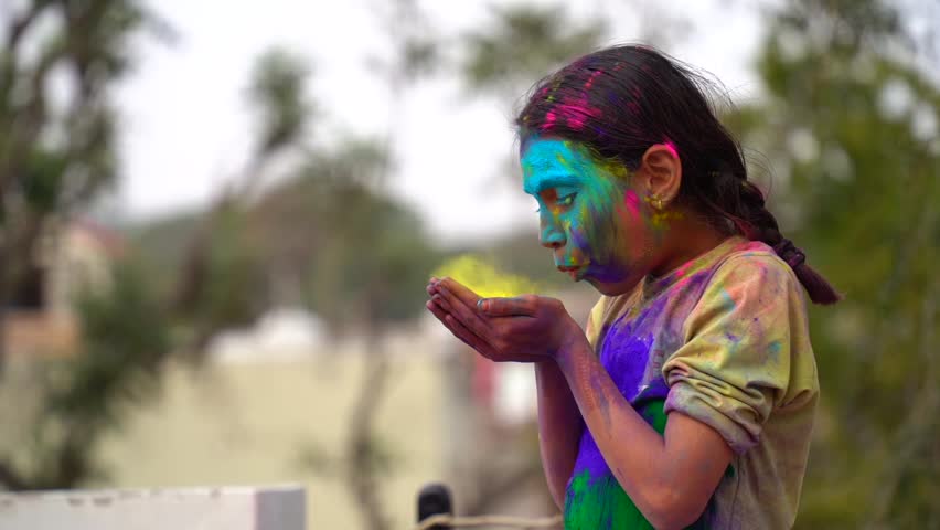 Kids blowing holi colour powder from hand during Holi festival celebration. Concept of young kids having fun by playing holi during festive