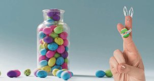 Animation of fingers with easter bunny and easter egg over jar of easter eggs on blue background. Easter, religion, christianity, tradition and celebration concept digitally generated video.