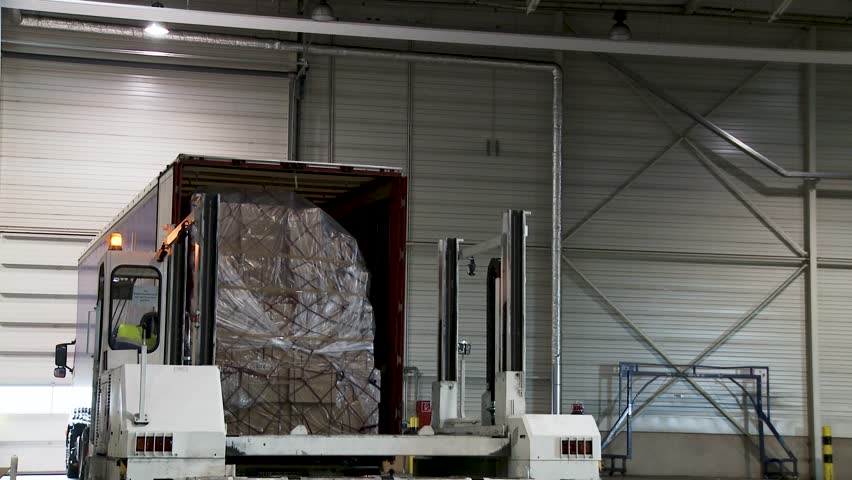 Forklift loading a large wrapped pallet into a truck at an indoor warehouse, worker visible - Powered by Shutterstock - Get 15% off with code: PIKWIZARD15