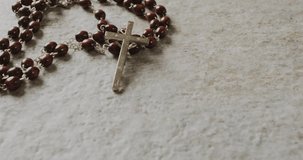 Animation of holy thursday text over christian rosary on grey background. Easter, religion, christianity, tradition and celebration concept digitally generated video.