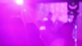People dance to the music of a DJ in a nightclub. Blurred video.