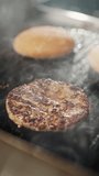 Street food, the process of cooking a burger on the grill, meat and bun are fried on the grill, burger ingredients, vertical slow motion video.
