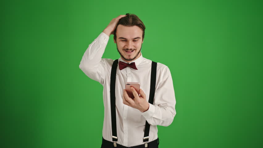 Disappointed Young Man in Bow Tie Reacting to Unpleasant News on Smartphone, Green Background Royalty-Free Stock Footage #3447757605