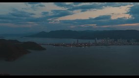 View from above over mountains, coastal city at dusk, 4k video