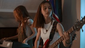 A girl musical duet at a rehearsal in the studio of a music school. One girl plays the bass guitar and the other plays the synthesizer. The girls rehearse under the guidance of a professional music - Powered by Shutterstock - Get 15% off with code: PIKWIZARD15