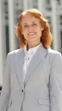 Redheaded businesswoman smiling at the camera with arms crossed