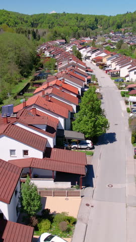 AERIAL: Terraced houses sprawl across the vast green expanse in Slovenia. Scenic aerial view of an idyllic suburban neighborhood near Ljubljana. Flying above a quiet suburbia on a sunny summer day.