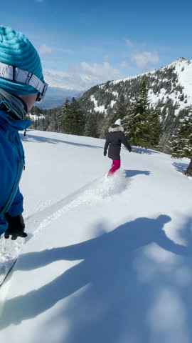 VERTICAL, SELFIE: Young Caucasian man and woman splitboard in the picturesque Slovenian backcountry on a sunny day. Tourist couple shreds fresh powder snow during a split boarding trip in Slovenia.