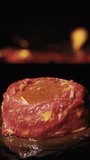A piece of beef for a fillet mignon against the background of fire, revolves. I put a sprig of rosemary Vertical video.