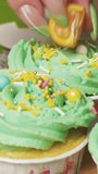 Decorate lemon cupcakes with mint cream cut in half mini tangerine. Close-up Vertical video.
