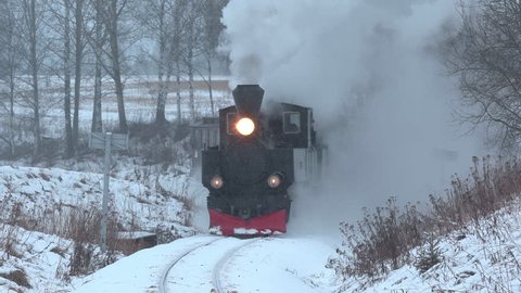URSKOG HOLAND TERTITTEN NORWAY - CA DECEMBER 2017: steam train railroad winter scenery approach curved tracks whistle blowing powerful engine