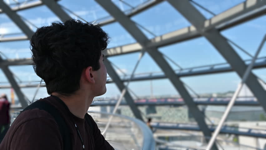 Berlin, Germany, August 15, 2023. Footage inside the glass and metal dome located on the roof of the Reichstag building. A young man looks around, blurred background, beautiful summer day.