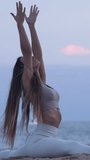Vertical video.Spanish woman practicing yoga in the sea during a sunset. 