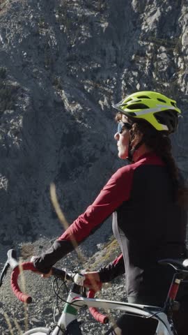 Vertical video. Portrait of cyclist woman on top of the mountain. 