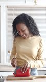 Vertical video. African American young woman cutting vegetables and cooking
