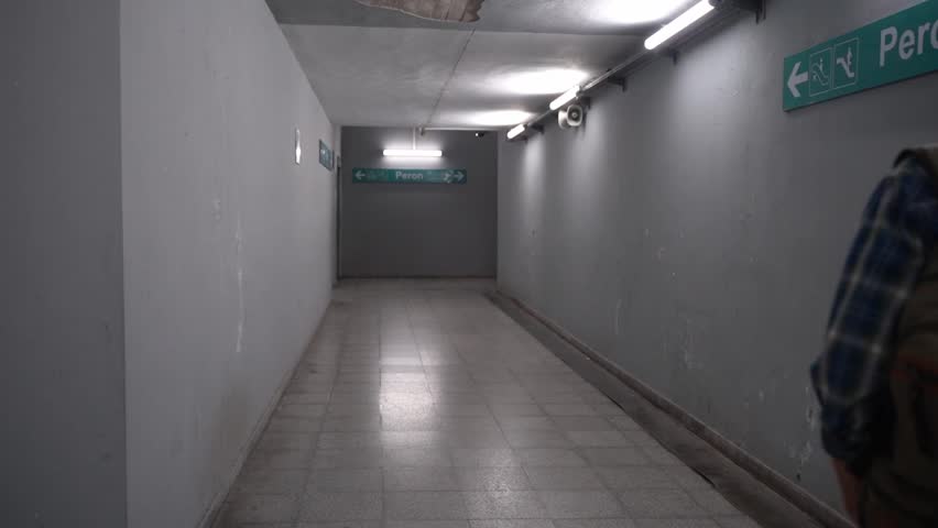 Middle-aged man walks on railway platform. Rear view. Public transport passenger takes a subway train. Suburban resident goes to work. Man with backpack use metro. Adult in Public transportation.