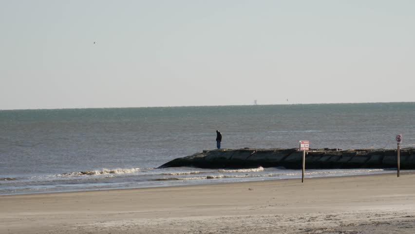 Man Standing on Rocks Over Gulf of Mexico on Cool Day