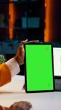 Vertical Video African american girl holding tablet with greenscreen layout, conducting data analysis for financial or economics courses. Student uses isolated mockup display on device, work from home