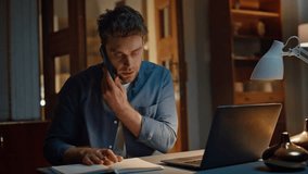 Busy guy communicating smartphone at evening workplace closeup. Serious handsome man talking cellphone discussing work news at night house. Focused freelancer holding pen preparing making notes alone - Powered by Shutterstock - Get 15% off with code: PIKWIZARD15