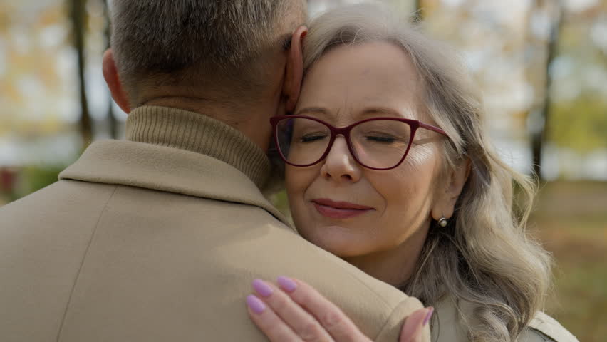 Close up mature woman close eyes leaning on man shoulder cuddling hugging feel love affection old couple female face and male back in city park outdoors retired family wife husband embrace hug cuddle Royalty-Free Stock Footage #3448314061