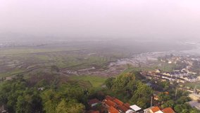 Hyper Lapse Footage. Aerial view of foggy rice fields in the morning in West Java Province, Indonesia. View of rice fields in a foggy morning. Video shot from drone in 4K 30fps resolution