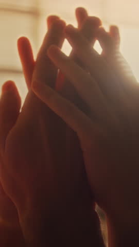 Vertical close up shot of affectionate lovers touching hands in room with cozy warm light