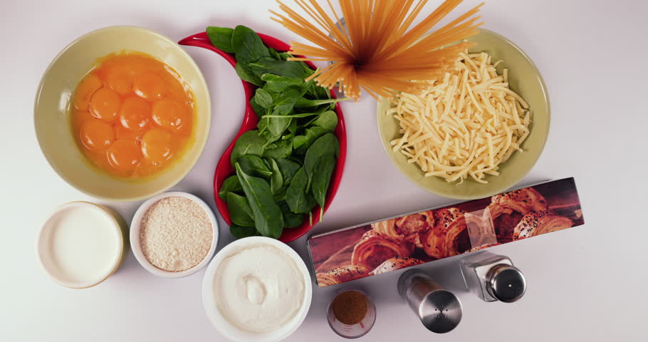 Fast Reverse speed up shot of lady putting down ingredients on a white table for a desert — Eggs, Spinach, Mozzarella, Condensed Milk, Ground Almond, Ricotta, Paprika, Dough, Salt and Pepper -4K 60pfs