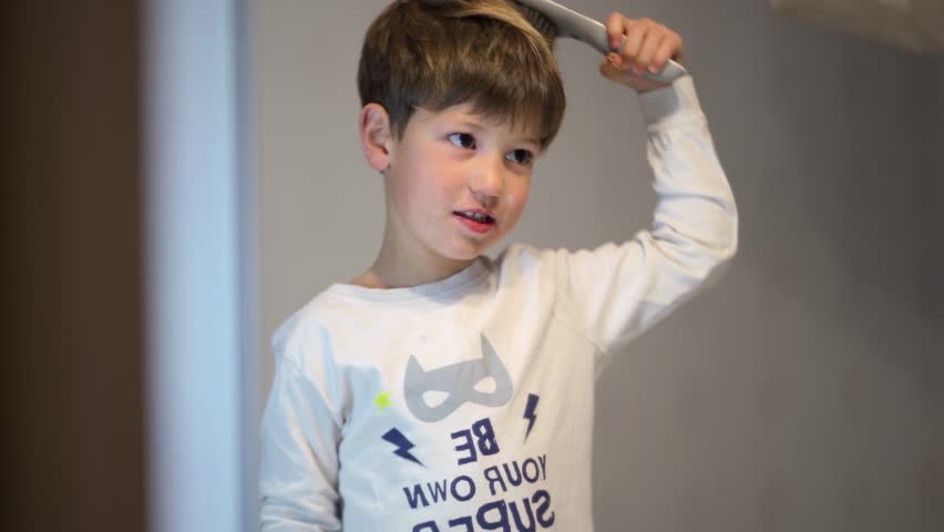 A child combing hair in the mirror of the bathroom