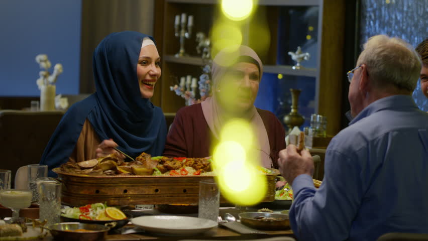 Elderly Man Telling a Funny Story to His Daughter, Wife and Son in Law. Joyful European Muslim Family Having Conversation and Enjoying the Eid or Ramadan Meal. Royalty-Free Stock Footage #3448697681