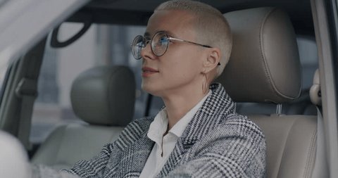 Slow motion portrait of cheerful young businesswoman turning to camera and laughing inside modern car. Automobile and businessperson concept. Stock-video