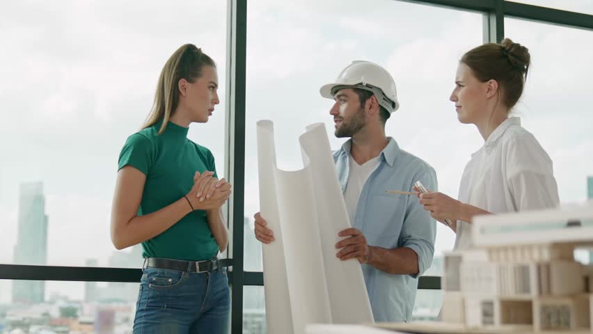 Professional architect engineer team thinking, sharing, brainstorming about design while looking at project plan. Young architect holding plan while manager listen and point at plan. Tracery