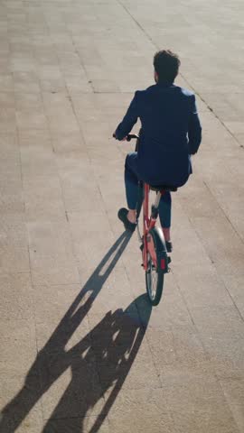 Rear view of unrecognizable business man riding a bike.