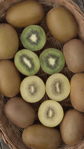 Top view of kiwifruit of different types colors (yellow and green) in a basket. Right and left spin seamless loop. Vertical video.