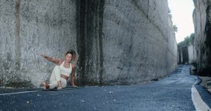 A young beautiful Latin woman with curly hair performs a yoga asana in a gorge between two large white rocks. Yoga classes in nature. Background video for yoga center and retreat. Wellness center.