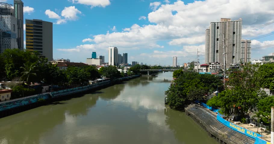 River between residential area in Metro Manila. Blue sky and clouds. Philippines.