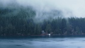 Cinematic rustic house hidden in evergreen rainforest covered by dense fog. Lake Crescent in Olympic National park. Scenic Washington nature 4K USA. Aerial view of mountain forest cabin at scenic lake - Powered by Shutterstock - Get 15% off with code: PIKWIZARD15