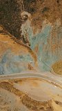 Weird dry landscape covered with moss and lichens. Motorway passing through the bare rocks of California coastline. Aerial view. Vertical video.