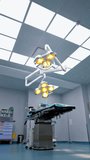 Big spacious light surgical room in modern hospital. Approaching rotating yellow light lamps hanging from the ceiling. Low angle view. Vertical video.