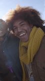 Vertical clip. Cheerful mixed race of group of friends taking selfie outdoors wearing winter clothes. Social media communication