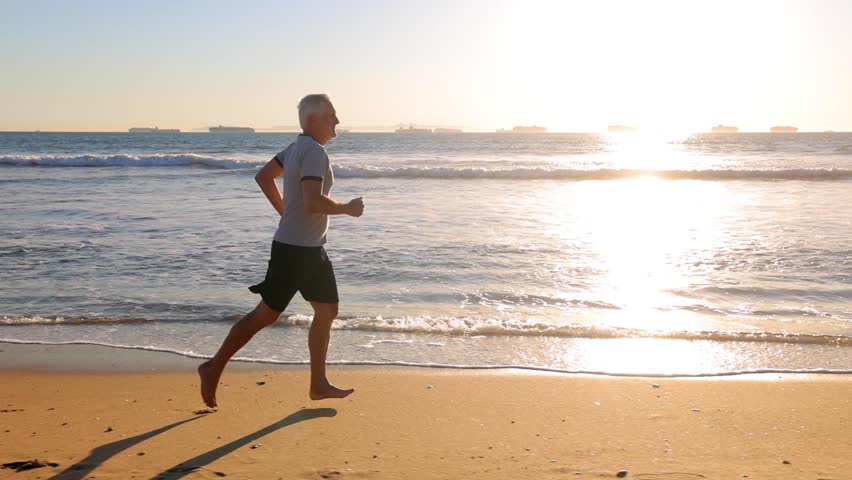 64 year old man getting his exercise at the beach at sunset. Slow Motion.