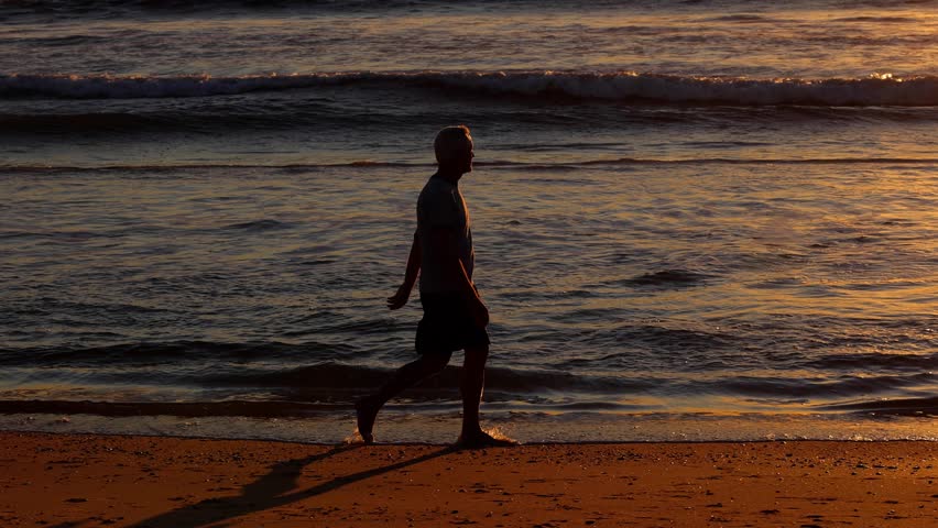 64 year old man getting his exercise at the beach at sunset. Slow Motion.