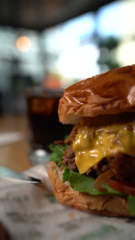 Vertical close-up of melted cheese between crispy burger at burger shop Royalty-Free Stock Footage #3449011689