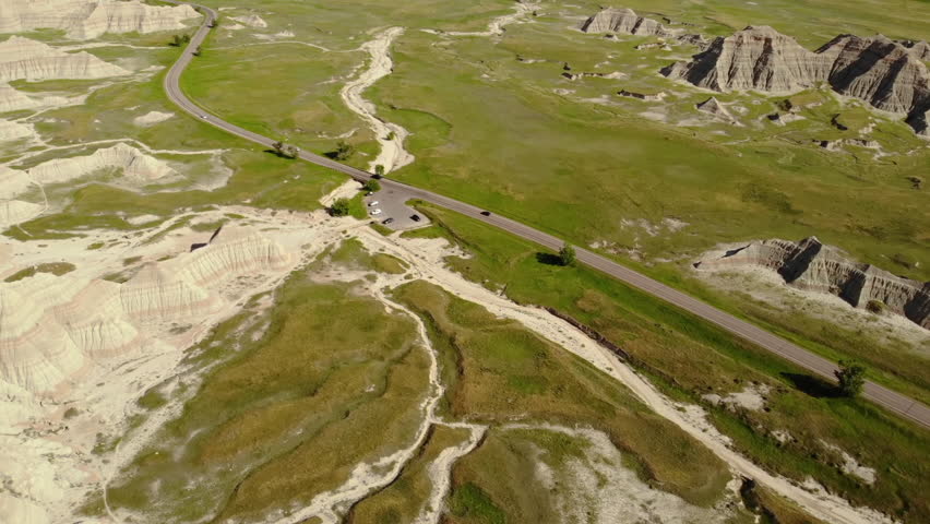 Aerial View of Badlands National Park, South Dakota USA. Rugged Sandstone Hills, Road and Prairie on Sunny Day, Drone Revealing Shot