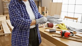 A mature woman wearing gloves in a carpentry workshop filled with tools and wood. - Powered by Shutterstock - Get 15% off with code: PIKWIZARD15