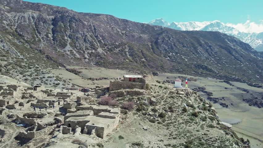 Travelers trekking at highland village ruines surrounded with unbelievable snow mountains, Nepal