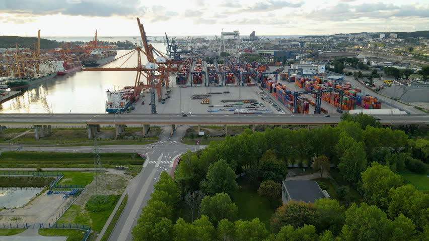 Aerial flight towards giant Dockyard in Gdynia during sunrise.Box with goods and freight delivery loaded on container ship