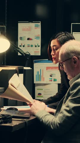 Vertical Video Private agents reading classified records to uncover new case clues, team strategizes next steps working in archive room. Detectives brainstorm strategies based on insights from old