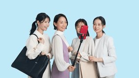 Group of Asian women taking selfies using smartphones and selfie sticks.