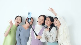 Group of Asian women taking selfies using smartphones and selfie sticks.